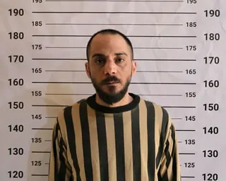 Amjad Youssef, wearing a striped uniform, stands in front of a height chart