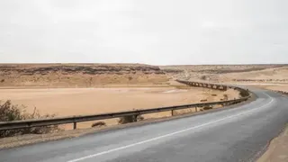 Universal Images Group via Getty Images a paved road cutting through a brown desert landscape
