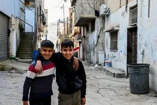 Two boys pose for a photo in a street in Askar refugee camp