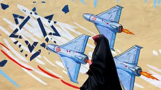 An Iranian woman walks past an anti-American and anti-Israeli mural on April 8, 2026 in Tehran.
