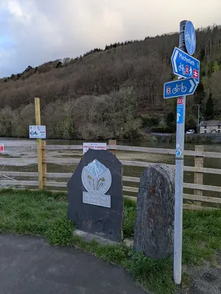 A road sign and an illustrated design on a stone block showing the border of the Snowdonia national park.