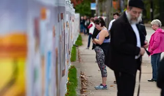 Visitors look at inspired artworks along the fence at the Tree of Life Synagogue on the first anniversary of the attack on October 27, 2019, in Pittsburgh, Pennsylvania.