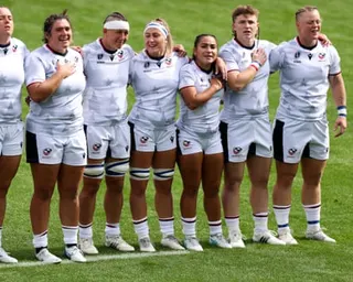 Members of the USA women’s rugby team stand in a line on a pitch