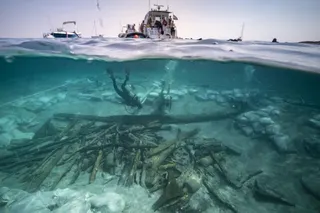 View of the excavation of the bow area of the Ilovik-Paržine 1 shipwreck. In the foreground, the cargo of logs and amphoras can be seen. Archaeologists are working near the structure of the bow complex.