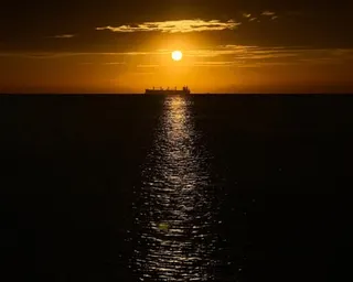 An oil vessel is visible in the Caribbean Sea at sunset