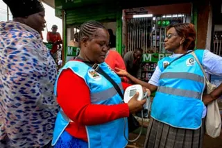 Three middle-aged African women, one holding a blood pressure monitor