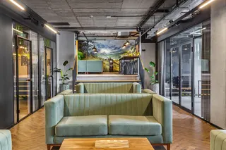 Green sofas and glass walls in the inside of a modern-looking office. It's Rebel Wolves' office in Poland, the developer of The Blood of Dawnwalker.
