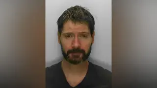 A mugshot of a man with short hair and a beard, facing the camera.