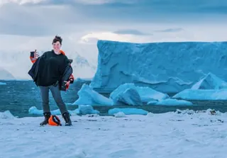 Kirsty Brooks stands in front of an iceberg in Antarctica