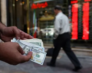 A currency dealer in Tehran holds $100 bills as the value of the Iranian rial fell last week.