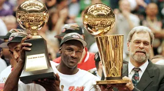 An image of Michael Jordan and Chicago Bulls head coach Phil Jackson lifting the Most Valuable Player trophy and the Larry O'Brien trophy respectively after winning game six of the NBA Finals with the Utah Jazz at the Delta Center in Salt Lake City