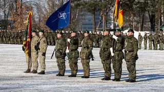 德國士兵身穿綠色迷彩軍服，在2026年2月4日於立陶宛考納斯舉行的公開儀式上列隊行進並高舉北約旗幟，標誌德國擴大對立陶宛的軍事承諾