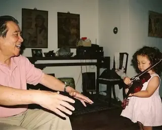 Laufey A childhood photo of Laufey shows her at home in Iceland, playing violin while her grandfather looks on, with a smile on his face