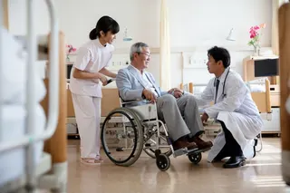 A doctor discussing with a senior man sitting in a wheelchair in a hospital ward in Tokyo, Japan. Photo: Getty Images