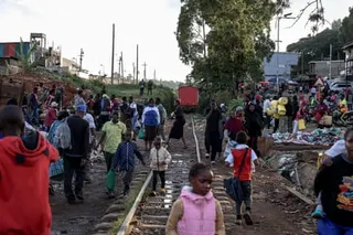 Africans walk along a railway track that runs through a shantytown