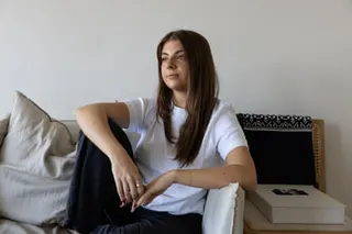 Maddy Mavrikis in her Sydney apartment, relaxing on a beige sofa