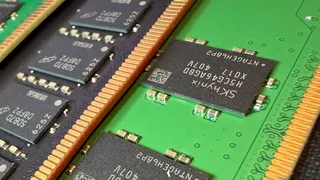 A close-up photo of a pair of Micron and SK Hynix DDR5 DIMMs, showing the memory modules on black/green PCBs