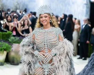 Woman on red carpet smiles while wearing sparkly silver dress with skeleton cutout