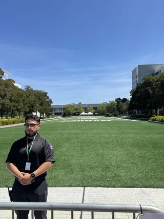Security guard standing behind a barricade, in front of EA's Madden field, which is empty