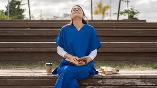 一名女子坐在長凳上，閉眼抬頭，做呼吸練習