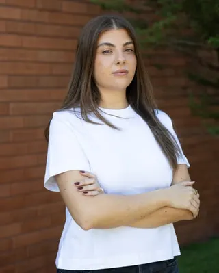 Maddy Mavrikis stands outside her apartment building with arms crossed