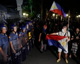 Police look on as a man holds out an upside down flag