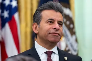 Marty Makary in a dark suit and patterned tie stands in front of an American flag
