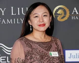 A woman posing for a photograph in front of a grey background.