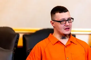 a man in an orange shirt sits in court crying