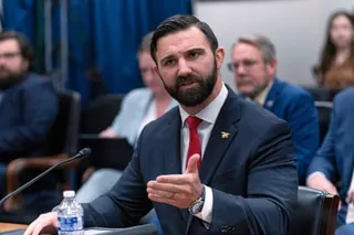 Cam Hamilton gestures while speaking into a microphone during a hearing.