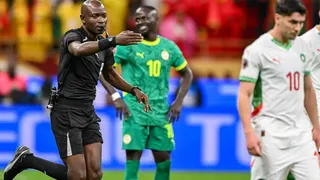 Referee Jean-Jaques Ndala, dressed in all-black kit and with a whistle held between his lips, points with his right hand for a penalty as he runs behind Morocco's Brahim Diaz, who dressed in white kit with red and green trim, after awarding a controversial spot-kick to Morocco in the final of the 2025 Afcon.
