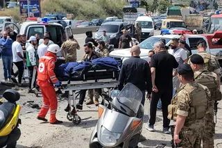First responders carry the body of a victim at the site of an Israeli drone strike that targeted a vehicle in the town of Jiyeh