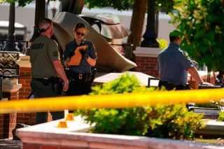 Three law enforcement officers stand near a playground slide cordoned off with yellow tape.