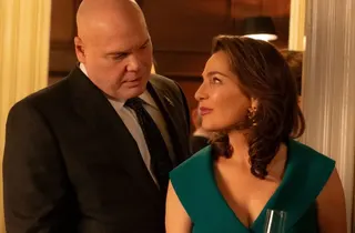 heavyset bald man in suit looking tenderly down at brunette woman in a green dress as she returns his affectionate gaze