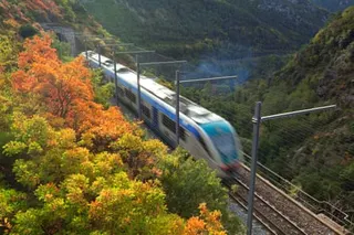 A blurred train crosses a valley in the Alpes Maritimes