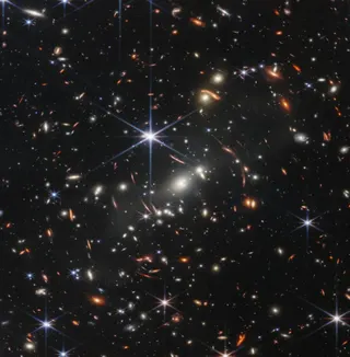 Image of a field of stars and galaxies, with most of them distorted by a gravitational lens.