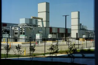 External view of Microsoft campus behind iron fencing with several tall white buildings and lower-rise industrial units.
