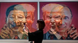一名參觀者於2025年8月2日在印尼泗水舉辦的ARTSUBS展覽期間，站在格蘭・祖基菲里（Galam Zulkifli）的藝術裝置旁，該裝置描繪了三國領導人（從左至右）：中國的習近平、美國的唐納德・特朗普與俄羅斯的弗拉基米爾・普京。