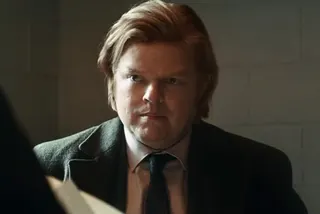 Closeup if young plump man with strawberry blonde hair in a suit, holding papers
