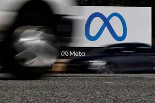 Cars drive past a Meta sign
