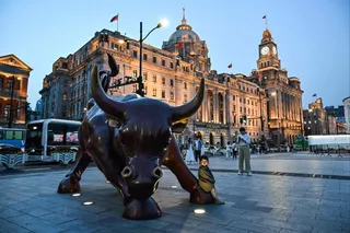 A girl sits on The Bund Bull sculpture in Shanghai on April 9, 2025. Photo: AFP