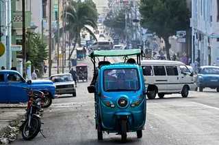People ride an electric tricycle along a street in Havana on May 13, 2026.