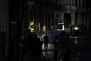 People walk on a street in near darkness in the Cuban capital