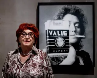 Valie Export poses for a photo in front of 'Self-portrait with cigarette kit' at an exhibition in 2023