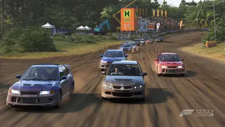 Dirt rally in Forza Horizon 6 with 12 cars taking a corner with banners and crowd infrastructure behind