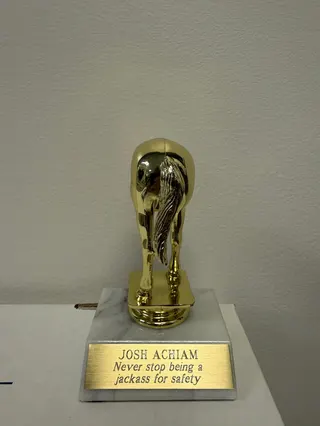 An image of what looks like a little league trophy but is in fact half a jackass (the animal) with the inscription “Never stop being a jackass for safety.”