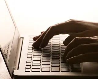 Two hands typing on a laptop keyboard