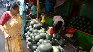2026 年 5 月 5 日，印度西里古里（Siliguri）一處市場區內，一名臨時路邊攤販正在販售夏季水果西瓜，攤位上堆放著多顆西瓜，供來往顧客選購