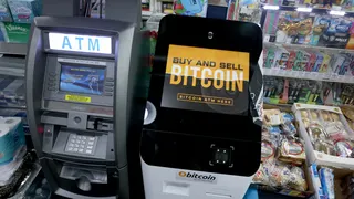 a Bitcoin ATM in a convenience store beside a traditional ATM