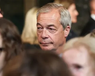 Nigel Farage among a crowd, looking to the side with a neutral expression